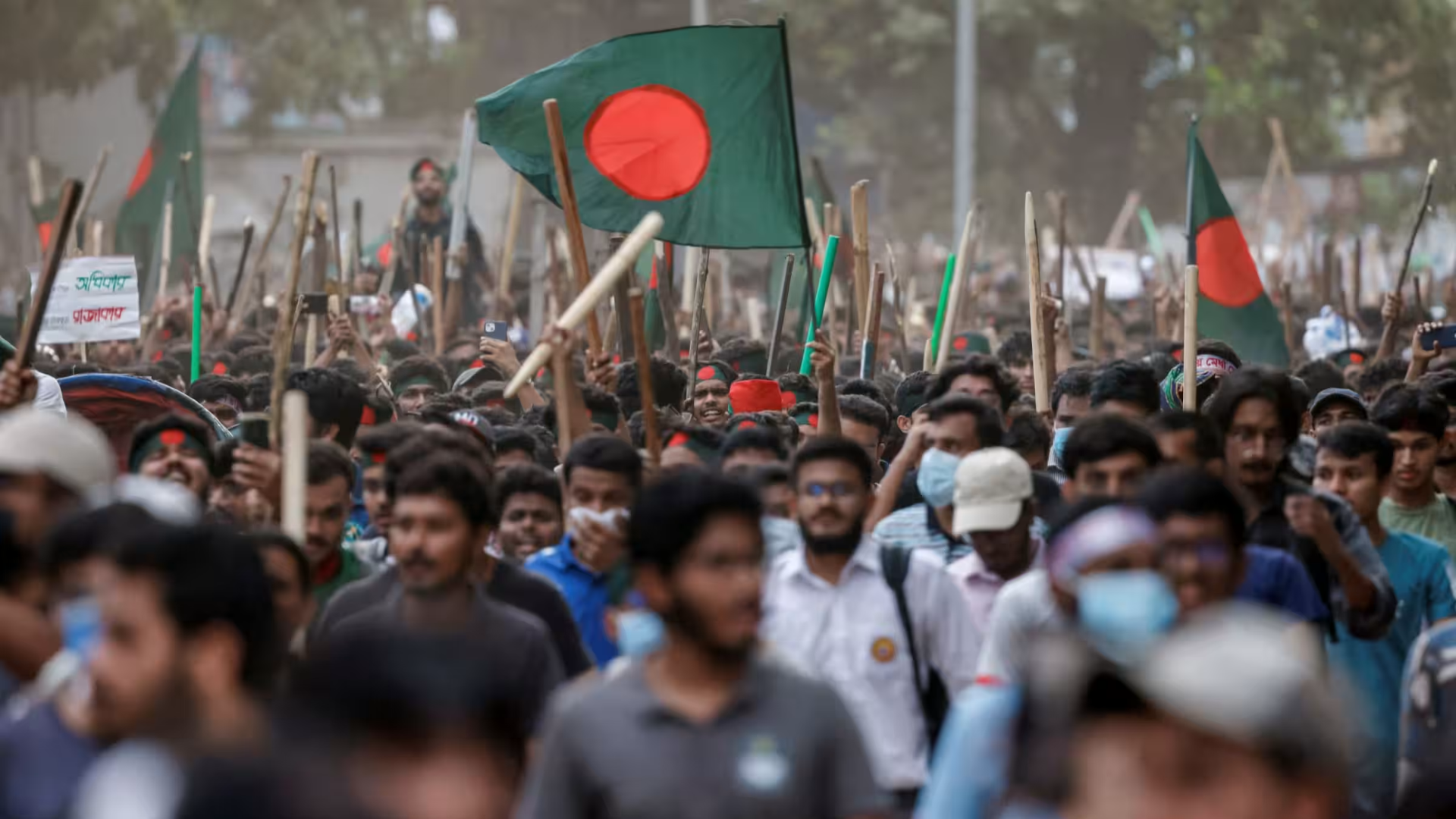Bangladeshi crowd marching with national flags during a community gathering